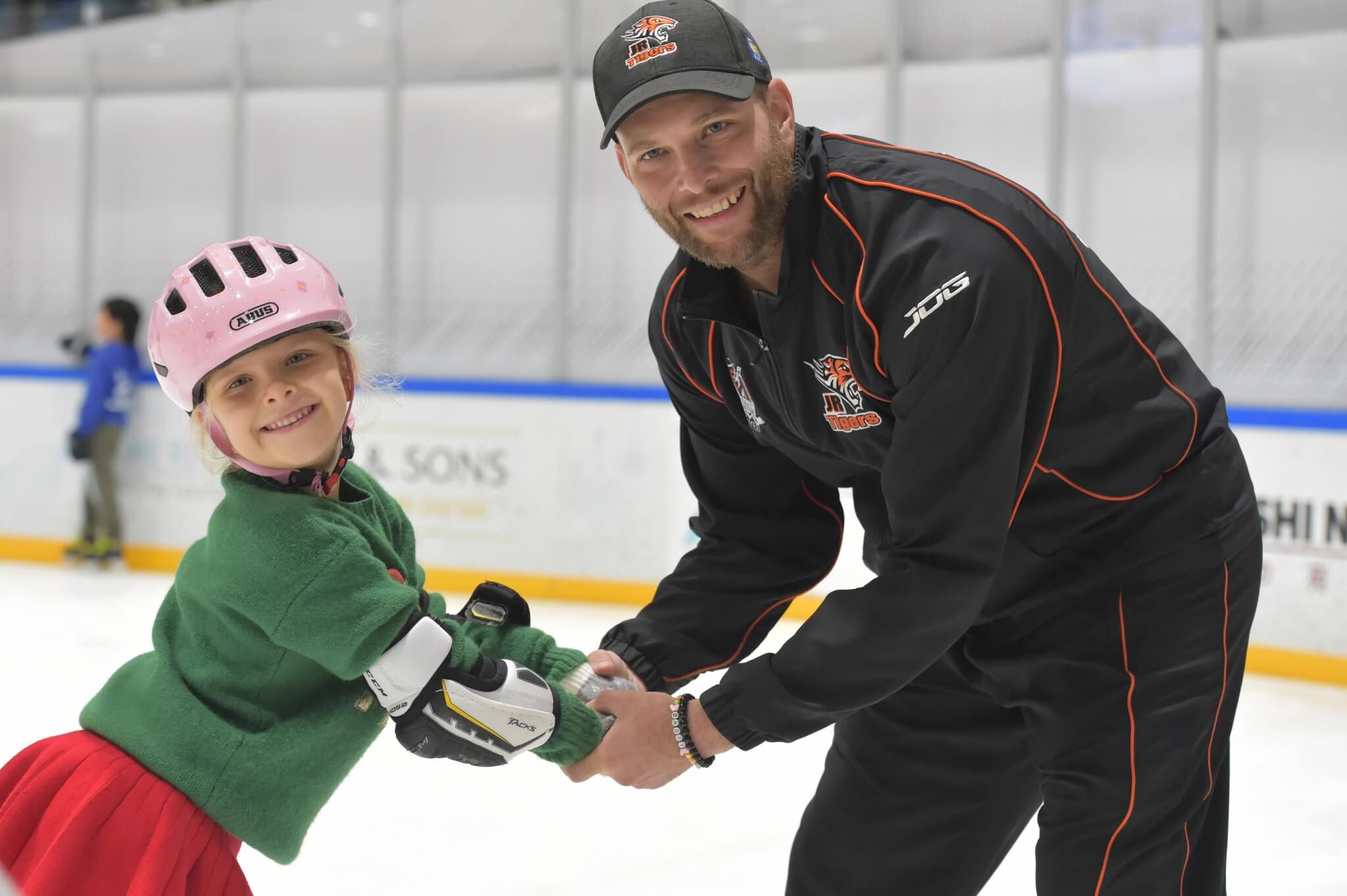 A hockey coach and a young girls at the Ice rink