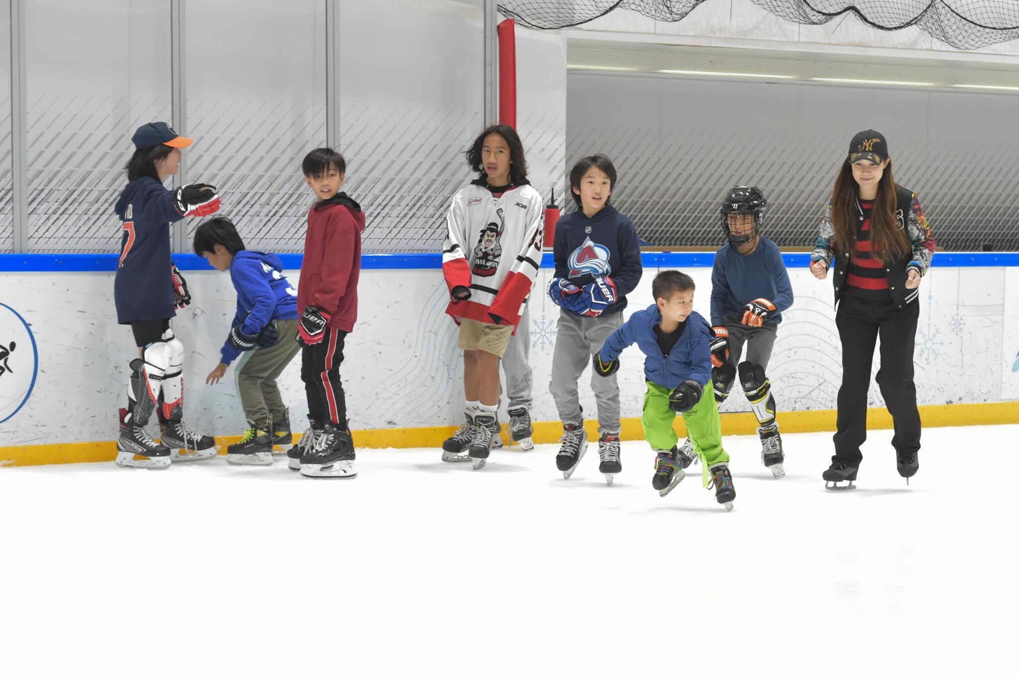 A group of kids and a woman ice skating